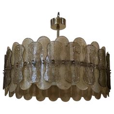 a glass chandelier hanging from a ceiling fixture with metal fittings and scalloped details