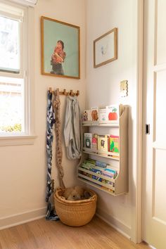 a room with a basket, coat rack and pictures on the wall next to it