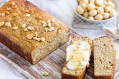 a loaf of bread sitting on top of a cutting board next to a bowl of nuts