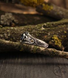 a silver ring sitting on top of a piece of wood next to a tree branch