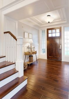 an empty entryway with wooden floors and white trim on the walls, along with stairs