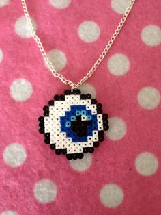 an evil eye necklace is shown on a pink polka dot surface with white dots around it