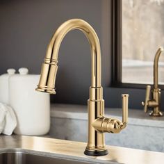 a kitchen sink with gold faucet and soap dispenser