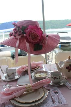 a pink hat on top of a table next to tea cups and utensils