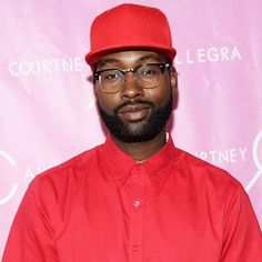 a man with glasses and a red hat stands in front of a pink backdrop that says court