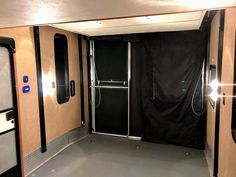 the inside of an enclosed trailer with black curtains and mirrors on each side of the door