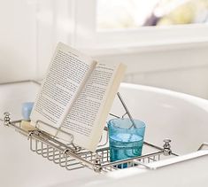 an open book sitting on top of a bath tub next to a glass filled with water