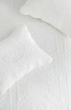 two white pillows sitting next to each other on top of a bed covered in white linens