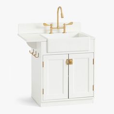 a white kitchen sink sitting under a faucet next to a wooden cabinet with brass handles