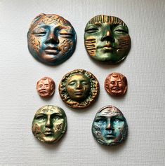 five different colored metal buttons with faces on them