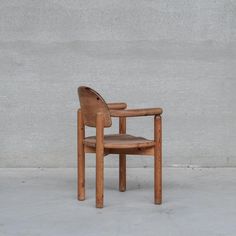 a wooden chair sitting in front of a cement wall