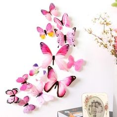 the pink butterflies are hanging on the wall and there is a vase with flowers in it