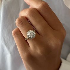 a woman's hand with a diamond ring on top of her finger and the engagement band