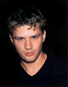 a close up of a person wearing a black t - shirt and looking at the camera