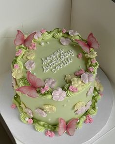 a green birthday cake with pink butterflies on it