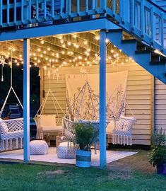 an outdoor patio with white wicker furniture and string lights hanging from the ceiling over it