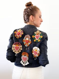 a woman wearing a denim jacket with embroidered hearts on it