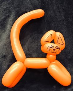 an orange cat balloon sitting on top of a black sheeted surface with its head turned to the side