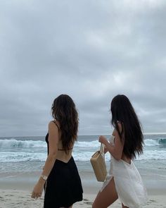 two women walking on the beach near the ocean