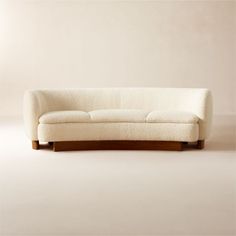 a white couch sitting on top of a hard wood floor next to a beige wall