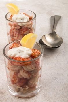 two glasses filled with food sitting on top of a counter next to a spoon and fork