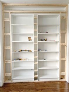 an empty room with white shelves and wood floors