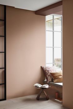 a bedroom with pink walls and a window in the corner that has an open book on it