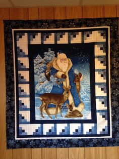 a quilt hanging on the wall with santa and his reindeers in front of it