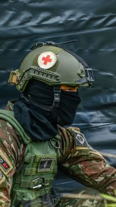 a man in camouflage with a red cross on his helmet