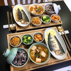 two wooden trays filled with different types of food on top of a black table