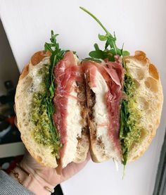 a person is holding two sandwiches with meat and veggies on them in their hands