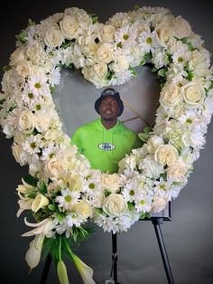 a heart shaped wreath with flowers and a golf player in the center is surrounded by white roses