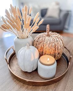 a tray topped with two white vases filled with different types of plants and candles