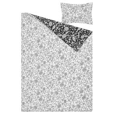 a white and black floral print bed spread with matching pillow cases on top of it