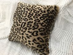 a leopard print pillow on top of a white bed