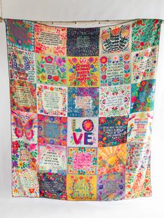 a multicolored quilt with words and flowers on it