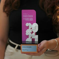 a woman is holding up an award for excellence in papelria, which she won