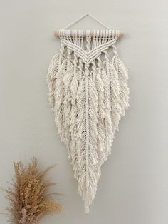 a white wall hanging next to a dried plant