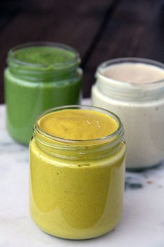 three jars filled with different colored food on top of a table