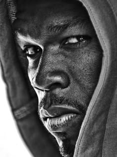 a black and white photo of a man in a hoodie looking at the camera