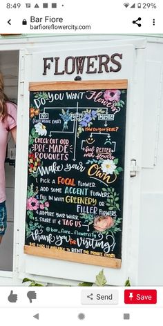 a woman standing in front of a chalkboard with flowers on it's side