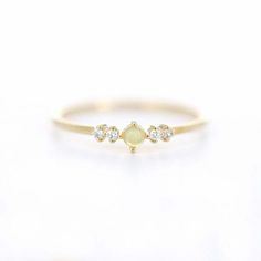 a yellow gold ring with three small white stones on the front and one diamond in the middle