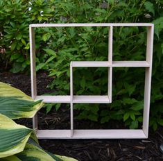 a white shelf sitting on top of a lush green field next to trees and bushes