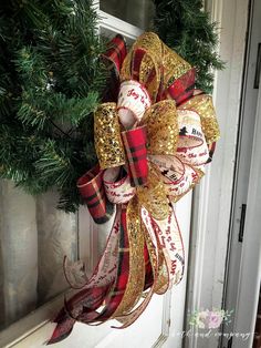 a christmas wreath with baseballs and ribbons hanging on the front door, decorated with evergreen branches