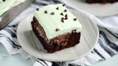 a piece of chocolate cake with mint frosting on a plate next to another slice