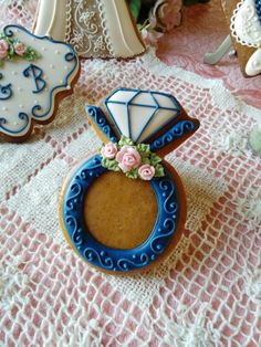 decorated cookies are sitting on a doily with lace and pink flowers in the background