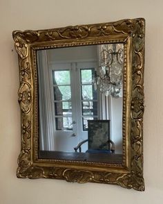 a mirror hanging on the wall above a desk with a chair in front of it