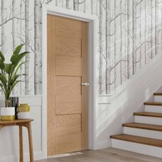 a wooden door sitting in the middle of a hallway next to a stair case and wallpaper