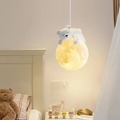 a teddy bear light hanging from the ceiling above a bed in a child's bedroom