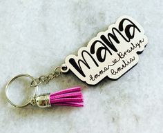 a pink tasseled keychain with the word mama on it, and a purple tassel